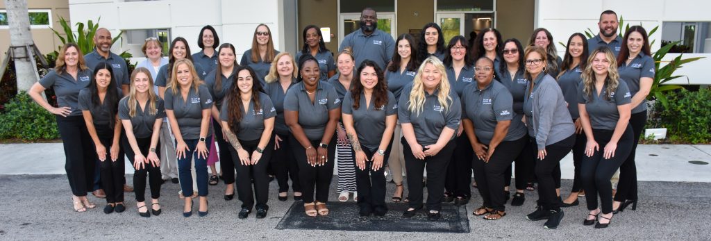 Group of smiling team members in matching uniforms outside a building