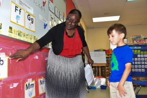 Teacher shows letter cards to a young student in a classroom