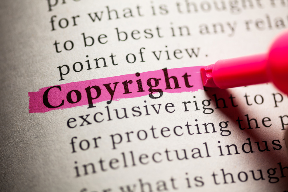 Close-up of the word "Copyright" highlighted in pink in a book, emphasizing its importance in protecting intellectual property.