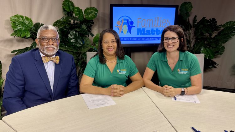 Three people sit at a table with "Families Matter" logo on shirts and screen.
